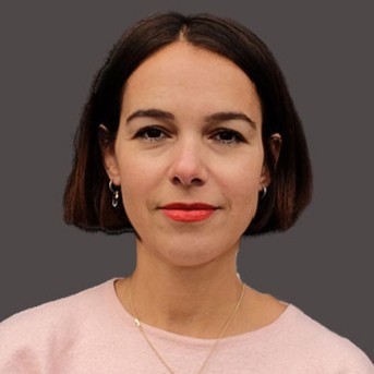 Close up of a white woman, woth dark hair styled with a bob, wearing a pink shirt,