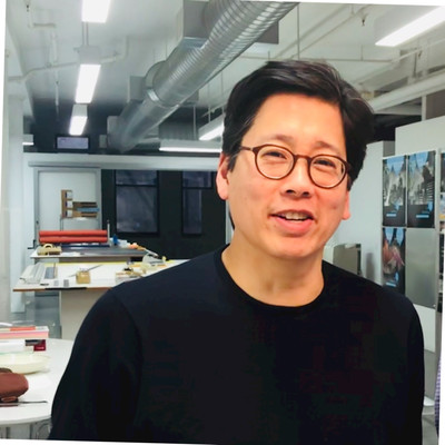 Close up of an Asian male, with short black hair and glasses, wearing a black long sleeve shirt 